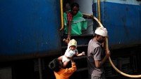 Bukanlah perkara mudah membawa air di kereta. Mereka harus berdesak-desakan dengan penumpang lain. Seringkali sumpah serapah mereka terima dari penumpang yang terganggu jalannya karena kendi air mereka menutupi jalan dan pintu (Francis Mascarenhas/Reuters)