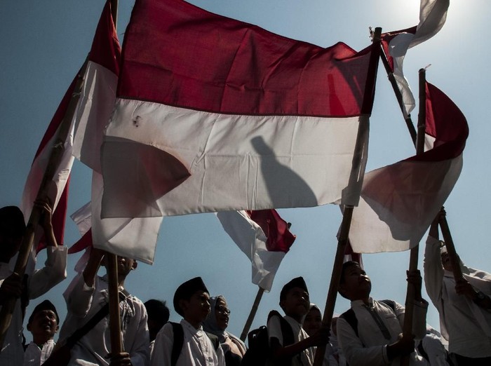 Sejumlah santri membawa bendera merah putih saat mengikuti upacara Peringatan Hari Santri Nasional Tingkat Provinsi Jawa Barat 2019 di Lapangan Gasibu, Bandung, Jawa Barat, Senin (22/10/2019). Pemerintah Jawa Barat memberikan sejumlah bantuan motor listrik dan hadiah umroh bagi santri, pondok pesantren serta DKM se-Jawa Barat pada  Peringatan Hari Santri Nasional 2019 yang bertema Santri Indonesia Untuk Perdamaian Dunia. ANTARA FOTO/Novrian Arbi/foc.