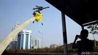 Seorang warga nampak memotret aksi para aktivis lingkungan dari Greenpeace Indonesia yang membentangkan spanduk di Patung Dirgantara.