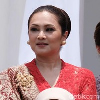 Menteri Sosial Juliari Batubara didampingi istrinya Grace Batubara. Grace memilih busana berwarna terang berupa kebaya modern berbahan lace warna merah. Penampilannya terkesan mewah dengan padanan kain songket dan bros emas. Sementara wajahnya dipercantik riasan smokey eyes dan lipstik nude. Foto: Andhika/detikcom