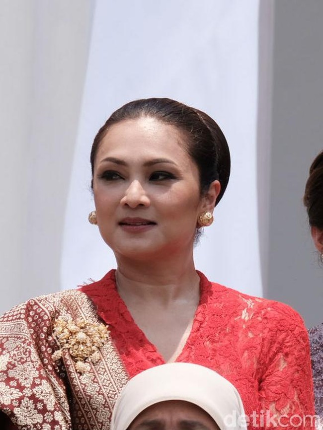 Menteri Sosial Juliari Batubara didampingi istrinya Grace Batubara. Grace memilih busana berwarna terang berupa kebaya modern berbahan lace warna merah. Penampilannya terkesan mewah dengan padanan kain songket dan bros emas. Sementara wajahnya dipercantik riasan smokey eyes dan lipstik nude. Foto: Andhika/detikcom