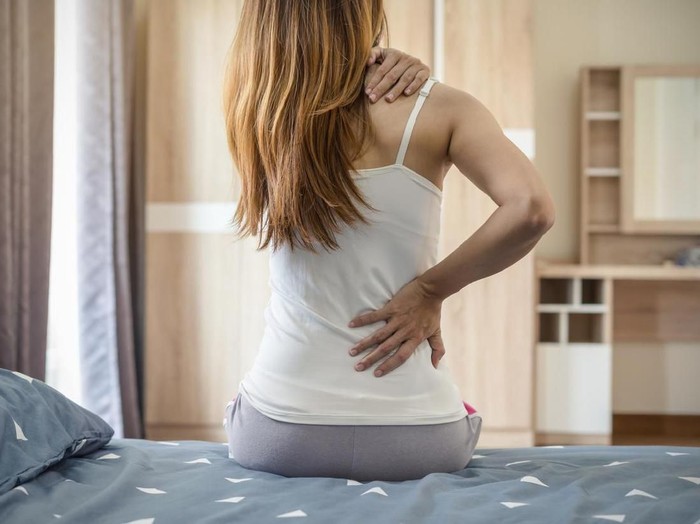 931082384 Woman suffering from back ache on the bed, healthcare and problem concept