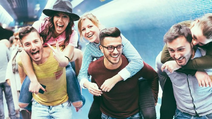 Group of friends having fun in underground metropolitan station - Young people hanging out ready for party night - Friendship and youth lifestyle concept - Focus on center girl face