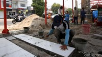 Seorang pekerja sedang sibuk memasang ubin lantai di lapak PKL tersebut.