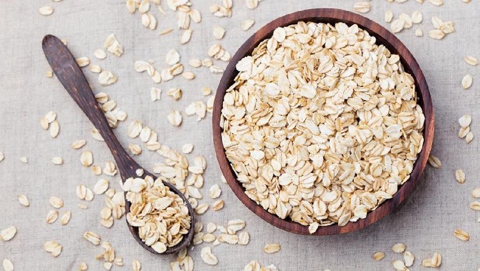 537316530 Healthy breakfast Organic oat flakes in a wooden bowl Grey textile background Top view Copy space