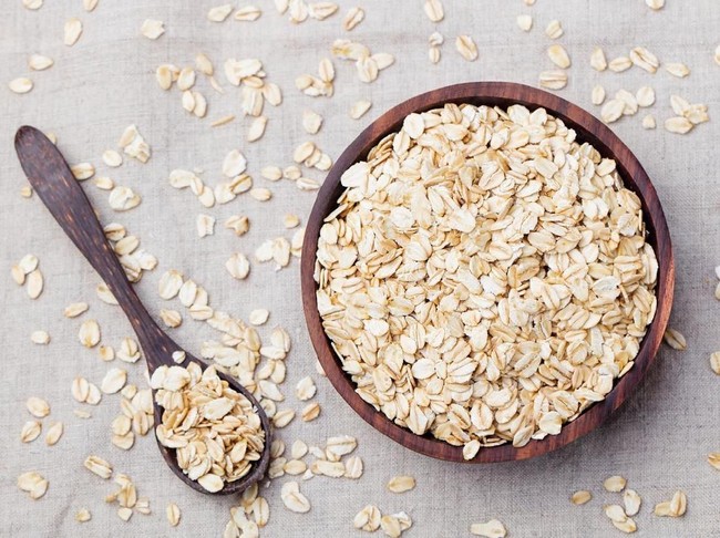 Healthy breakfast Organic oat flakes in a wooden bowl Grey textile background Top view Copy space