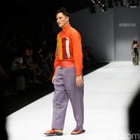 Disusul Mike Lewis, yang juga mengenakan rancangan Sebe11as, berupa kemeja oranye dengan aksen patchwork dipadu celana lebar abu-abu.  Foto: Rachman Haryanto/detikcom