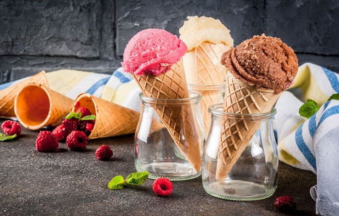 es krim Summer sweet berries and desserts, various of ice cream flavor in cones pink (raspberry), vanilla and chocolate with mint on dark background copy space