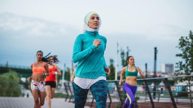 997638900 Multi ethnic group of young  women exercise outdoor, next to the river. They are wearing sport clothing, running, stretching, celebrate and support each other.