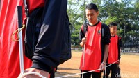 Para peserta mengikuti aksi gerak jalan dengan menggunakan tongkat putih dan berpegangan pada seutas tali yang saling terhubung dengan peserta aksi gerak jalan lainnya.