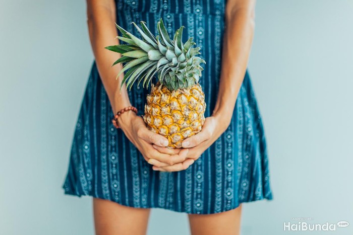 Young woman holding pineapple, close up of fruit