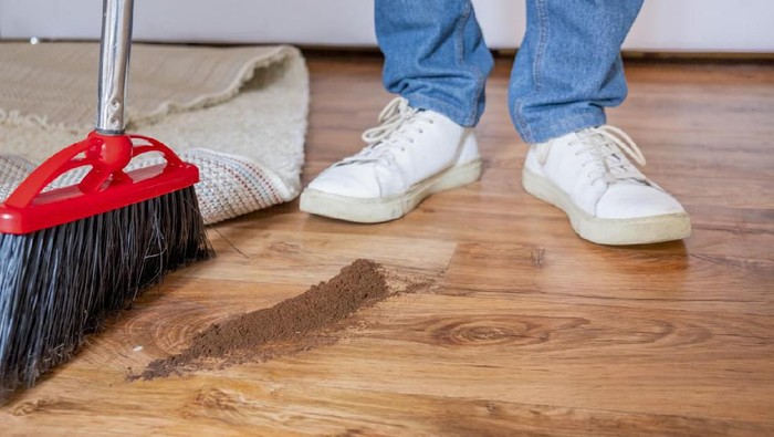 Closeup cleaning man sweeping wooden floor with broom