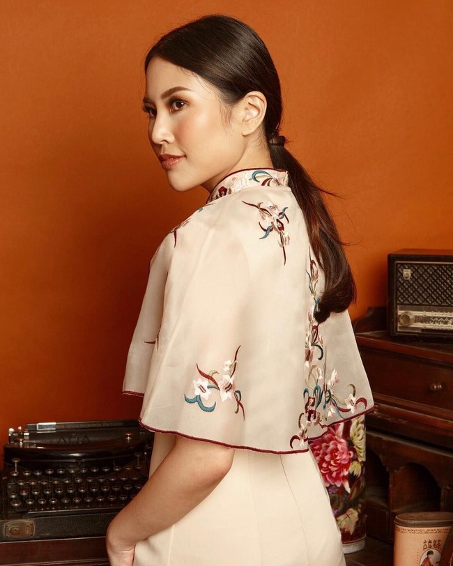 Gaya oriental ditampilkan Angela lewat busana cheongsam berpotongan cape. Busananya juga dihiasi ornamentasi oriental dengan motif floral. Foto: Instagram/@angelatanoesoedibjo