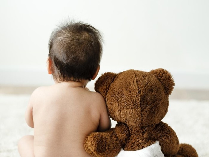 Back of a baby with a teddy bear