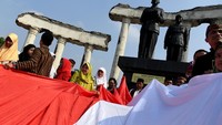Wali Kota Surabaya Tri Rismaharini (kelima kiri) turut serta membentangkan bendera Merah Putih bersama sejumlah pelajar saat Upacara Sumpah Merah Putih yang digelar dalam rangka peringatan Hari Sumpah Pemuda tengah berlangsung di Tugu Pahlawan, Surabaya.