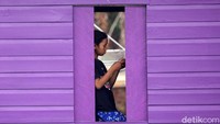 Seorang anak tampak bermain smartphone di depan jendera rumahnya.