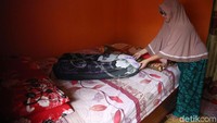 Pemilik Homestay Dewi sedang merapihkan tempat tidur.