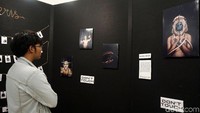 Seorang pengunjung tampak serius melihat foto-foto yang dipamerkan.