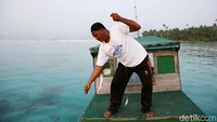 Anam menarik senar pancingnya setelah umpan dimangsa oleh ikan.