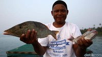 Anam menunjukkan ikan hasil memancingnya.