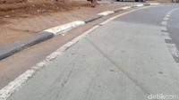 Terlihat garis ban di jalan dekat trotoar.