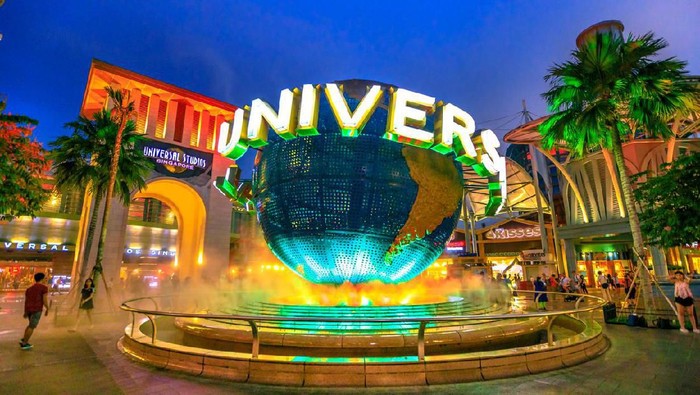 Singapore - May 2, 2018: Universal Studios world globe in green light, with tourists visiting this Hollywood movie theme park in Sentosa island.