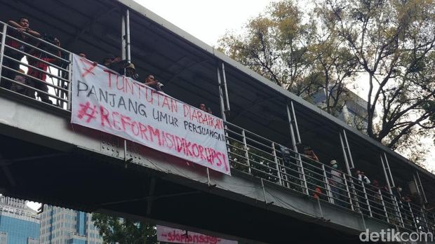 Massa di Patung Kuda mencopot spanduk Seknas Jokowi dan menuliskan #ReformasiDikorupsi di spanduk itu.