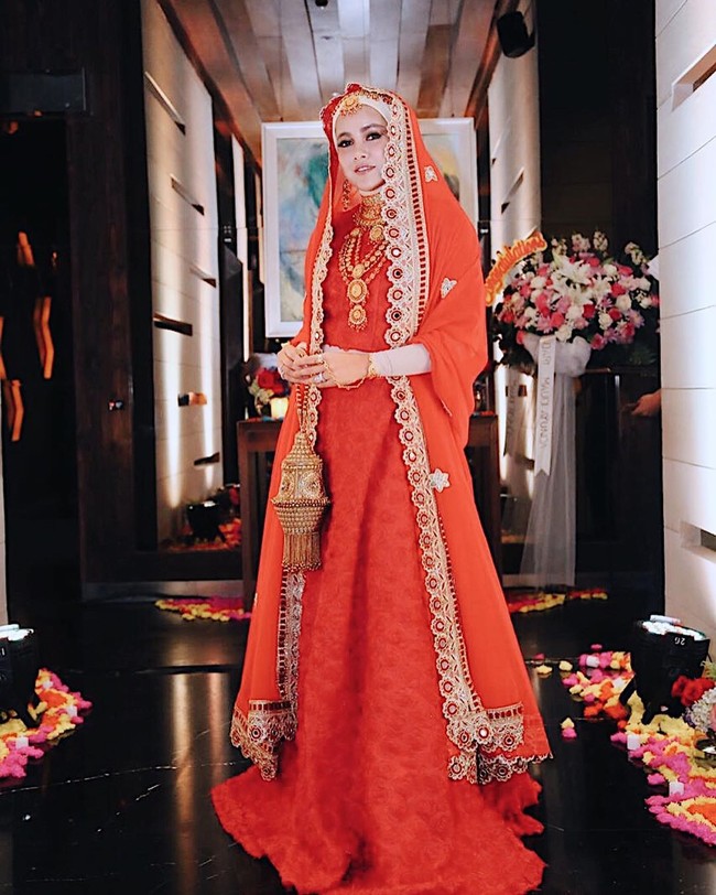Olla Ramlan yang sudah berhijab juga bergaya ala wanita India dengan dress dan kerudung merah - emas. Olla melengkapi penampilannya dengan membawa tas emas yang bentuknya mirip lampu. Foto: Dok. Instagram