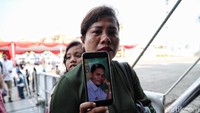 Seorang ibu menunjukan foto keluarganya yang menjadi korban dalam peristiwa tersebut.