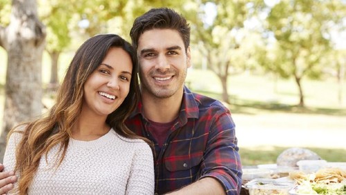 Young couple is hugging and taking selfie at the front of the fountain