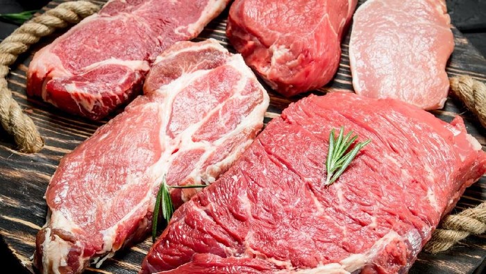 1141775085 Raw meat. Beef and pork steaks with spices on the cutting Board. On a black rustic background.