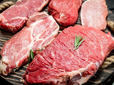 Raw meat. Beef and pork steaks with spices on the cutting Board. On a black rustic background.