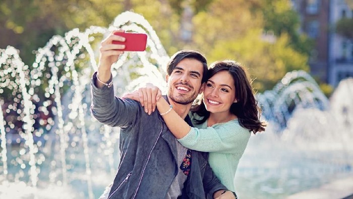 zodiak Young couple is hugging and taking selfie at the front of the fountain