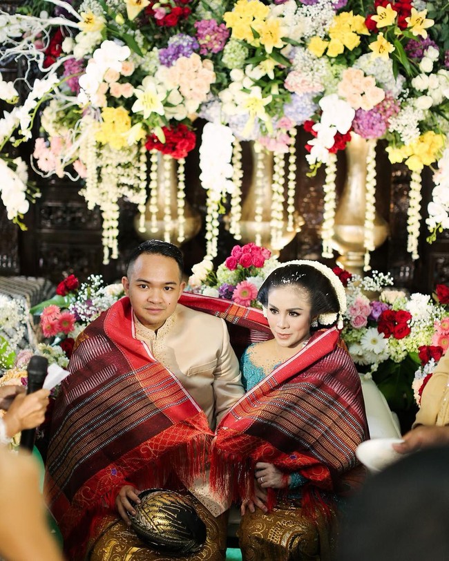 Prosesi tujuh bulanan Momo Geisha dan terbilang unik. Ia dan sang suami, Nicola Reza Samudera menggabungkan adat Batak dan Jawa dalam gelaran tujuh bulanan pada Februari 2019 lalu. Berkebaya lace warna toska, Momo Geisha tampil ayu dengan sanggul tradisional. Foto: Instagram/@therealmomogeisha