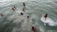 Bergantian anak-anak tersebut melompat dari atas dermaga lalu berenang di laut tersebut.