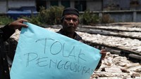 Warga membentangkan poster menolak penggusuran.