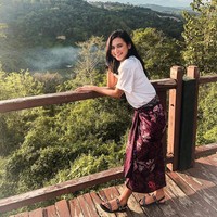 Indah tampak selalu bangga tampil dengan kain-kain tradisional. Saat berlibur dan menikmati pemandangan, Indah tampil kasual dengan kaus dan kain lilit batik.  Foto: dok. Instagram @indahpermatas