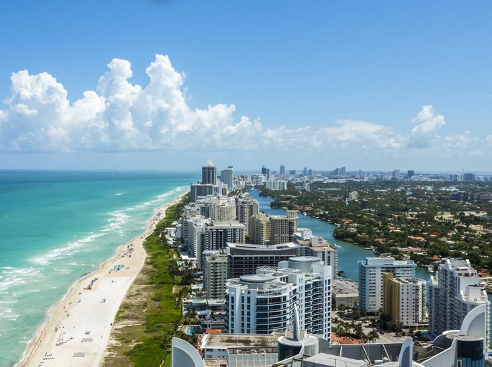 Looking down South Beach in Miami. Full view of the beach on the left and the city on the right. Beautiful blue sky on a clear day.
