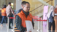 Jumari berjalan memasuki gedung KPK dengan menutupi tangan yang diborgol dengan kertas.