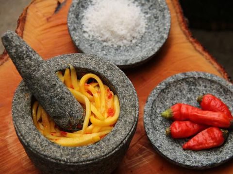A popular Indonesian condiment of red chili peppers and tomato paste in traditional mortar and pestle is sambal ulek