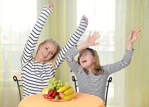 Excited female raising fist and cheering while watching sport on mobile phone in campus