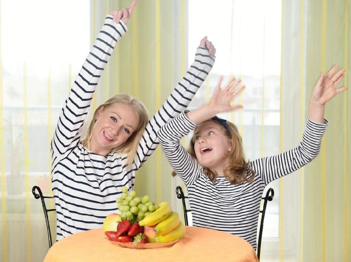 Excited female raising fist and cheering while watching sport on mobile phone in campus