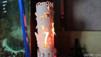 Setelah gambar terukir, Adhe melubangi beberapa sisi gambar tersebut, kemudian memasukkan lampu di celah pipa.