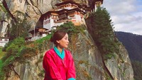 Anggunnya dai berfoto mengunakan baju khas Bhutan dengan latar Kuil Paro Taktsang (pindapandaonly/Instagram)