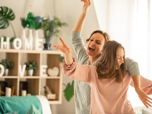 Young happy women talking and laughing while drinking coffee together in coffee shop.