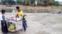 Seorang pedagang jajanan berjualan di tengah bengawan solo yang kering.