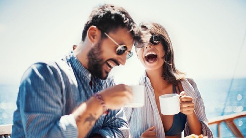 Young happy women talking and laughing while drinking coffee together in coffee shop.