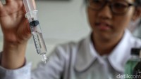 Seorang anak menakar air yang akan dituangkan ke media tanam.