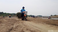 Warga dengan santai menyeberang menggunakan motor melewati tengah sungai bengawan yang kering.