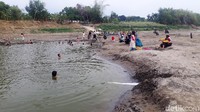 Warga dan anak anak desa Kedungprimpen bermain di cekungan yang berisi air yang kotor dan menguning. 